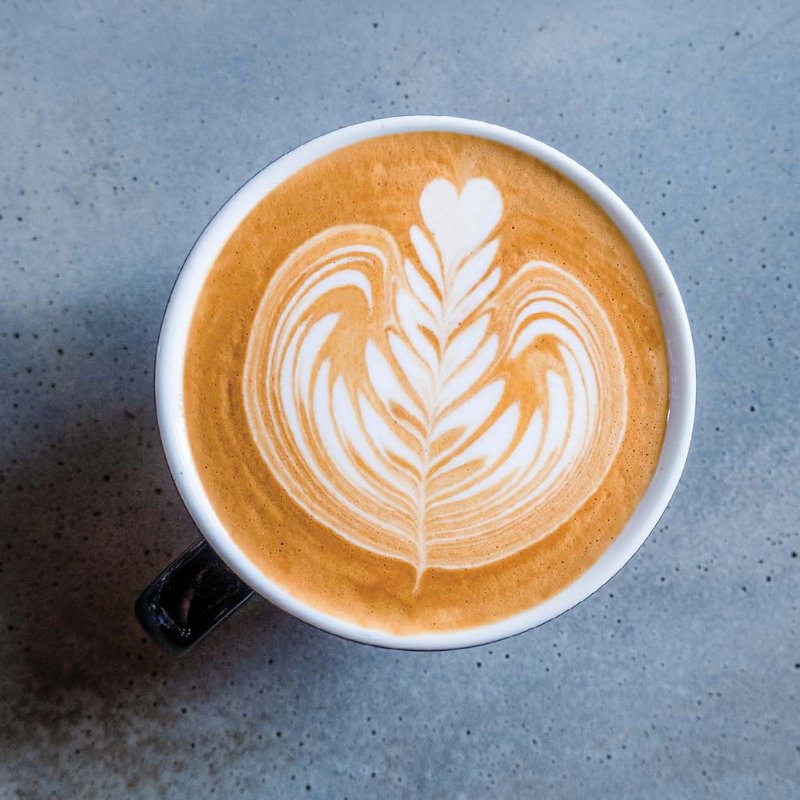 Une tasse de café présentant un latte, le dessin en latte art est une rosetta