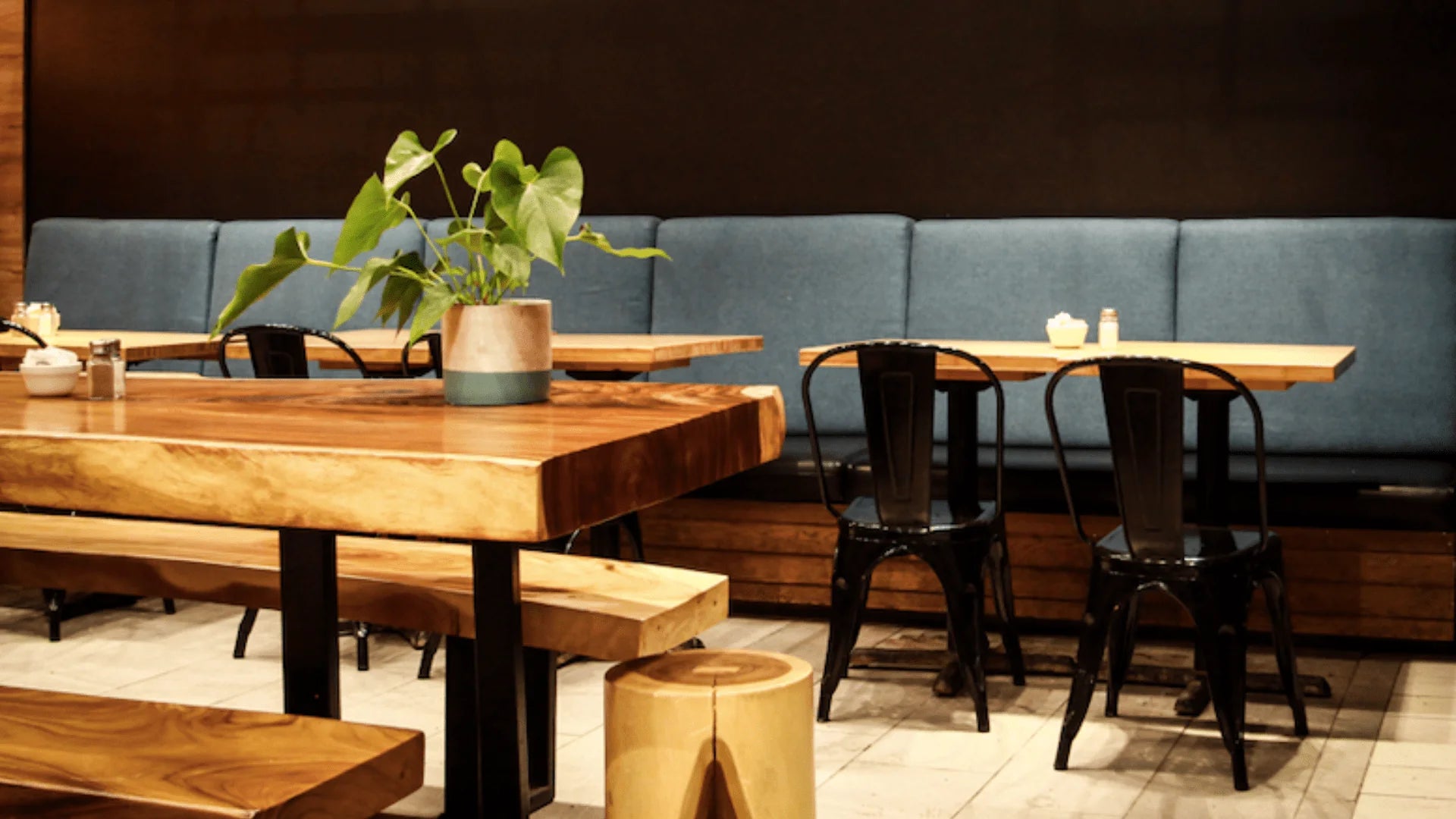 ointérieur d'un coffeeshop présentant des tables en bois et des chaises noires